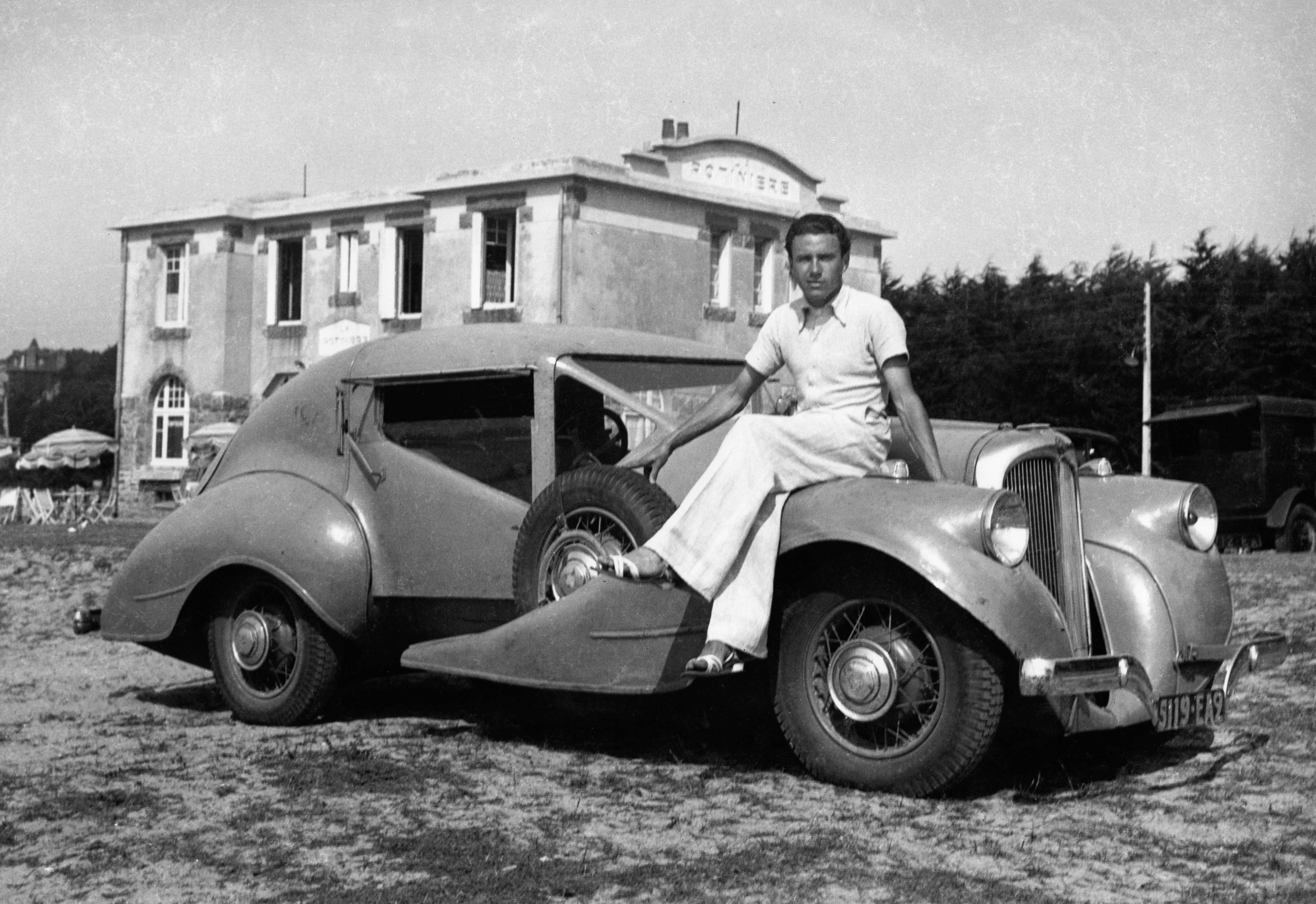 Roger Le Flanchec posant sur sa voiture de course. Cl. anonyme. Nd © Fonds Roger Le Flanchec. SIAF/CAPa/Archives d’architecture du XXe siècle. 051 Ifa